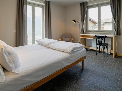 a bedroom with a bed with a desk and windows at Il nido di Siro in Cercino