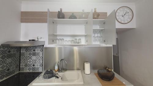 a kitchen with a sink and a clock on the wall at Appart Cosy proche Gare - Lit Queen size & Netflix in Angoulême