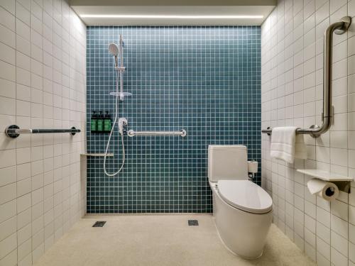 a bathroom with a toilet and a shower with blue tiles at voco Bangkok Surawong by IHG in Bangkok