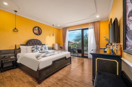 a bedroom with a king sized bed and a balcony at JM Hoi An Beach Hotel - Free Shuttle Car To Old Town in Hoi An