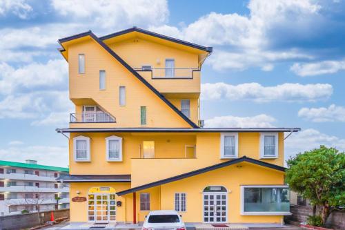 a yellow building with a car parked in front of it at 観光名勝千畳敷徒歩2分 shirahamaペンション千畳嵐