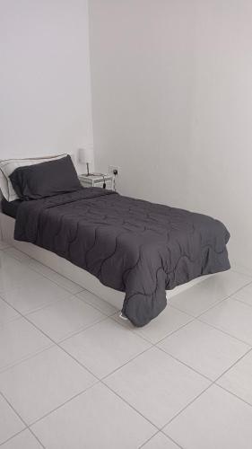 a bed with a black comforter in a white room at BB Homestay in Tuaran