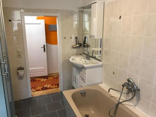 a bathroom with a tub and a sink and a mirror at Bergapartments in Kurort Oberwiesenthal