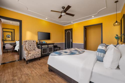 a bedroom with a bed and a chair and a television at JM Hoi An Beach Hotel - Free Shuttle Car To Old Town in Hoi An