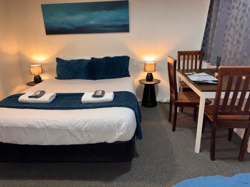 a bedroom with a bed and a desk and a table and chairs at Wairoa Motel in Wairoa