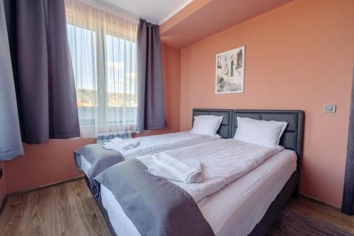 two beds in a bedroom with orange walls and a window at Rila View Apartments in Samokov