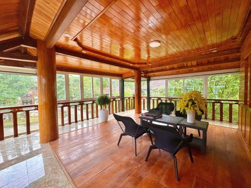 Kon PlongGià Làng Măng Đen Homestay的大型客房铺有木地板,配有桌椅。