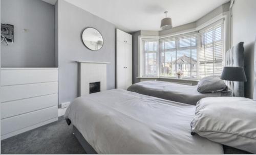 a bedroom with two beds and a mirror and a window at Recently renovated 3 bed home in Southampton
