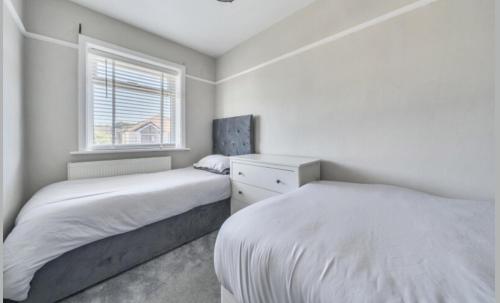 a white bedroom with two beds and a window at Recently renovated 3 bed home in Southampton