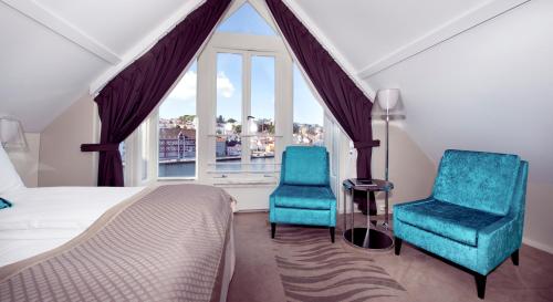 a bedroom with two chairs and a bed and a window at Clarion Collection Hotel Skagen Brygge in Stavanger