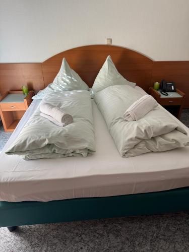 a bed with three pillows on top of it at Hotel & Restaurant Garda in Darmstadt