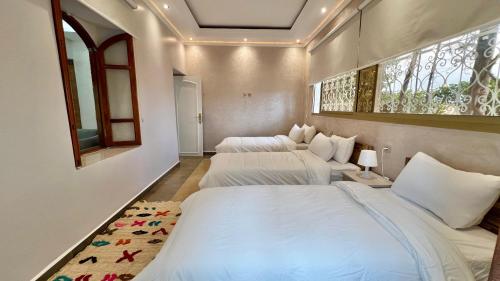 Dos camas en una habitación con dos ventanas. en Villa de rêve avec Piscine privée & Petit-déj gratuit, en Oulad Raho
