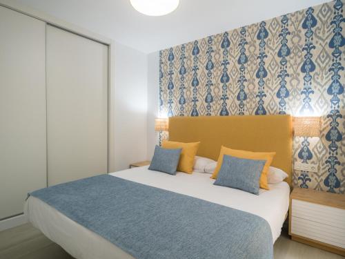 een slaapkamer met een groot bed met blauwe en gele kussens bij Sunset Arguineguin by CanariasGetway in Arguineguín