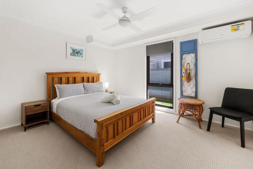 een slaapkamer met een bed, een stoel en een raam bij Whale Watcher - Beachfront with Spa in Culburra Beach