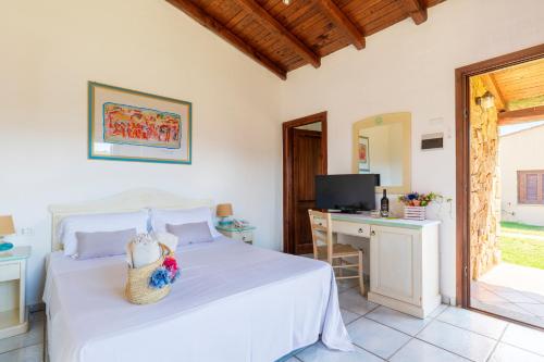 ein Schlafzimmer mit Bett, Schreibtisch und Fernseher in der Unterkunft Li Suari Club Village in San Teodoro