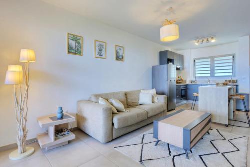 Una sala de estar con un sofá y una cocina. en Le Nocéa - apt T3 Saint Leu, en Saint-Leu