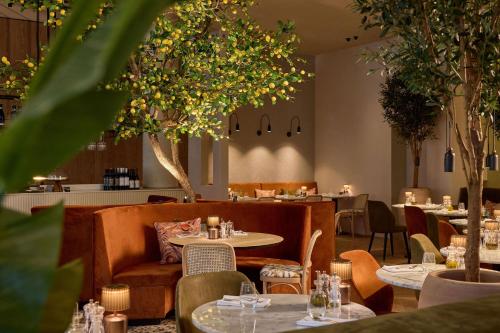 Van der Valk Hotel Gent في خنت: مطعم به طاولات وكراسي وأشجار