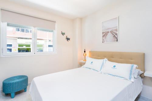 a white bedroom with a bed and two windows at El Médano Beach Apartment, Central & Bright in El Médano