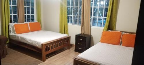 two beds in a room with windows at Boquete Guest House in Puente Cochea