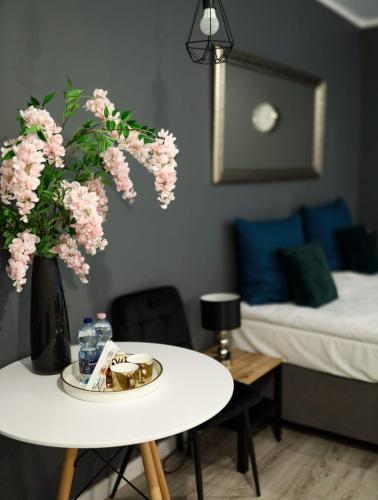 a room with a table with a vase of pink flowers at Apartament Roma in Pniewy