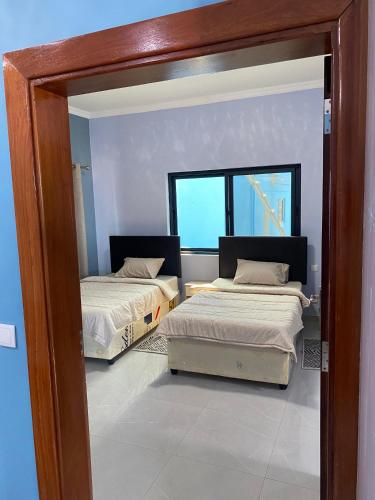 two beds in a room with a window at Villa Djonasse, a Residence of Exellency in Fombeni