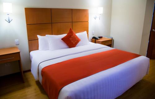 a bedroom with a large bed with orange and white pillows at Xima Exclusive Cusco in Cusco
