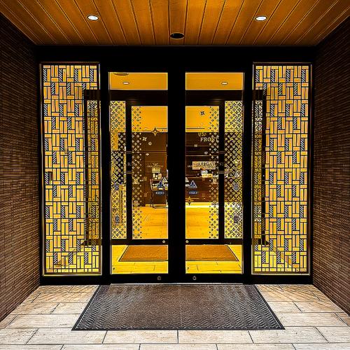 a glass door of a building with a yellow door at Arigato Stay Kanazawa Katamachi in Kanazawa