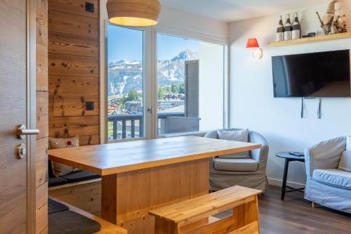 a living room with a wooden table and a large window at La Foret du Praz 501 in Courchevel