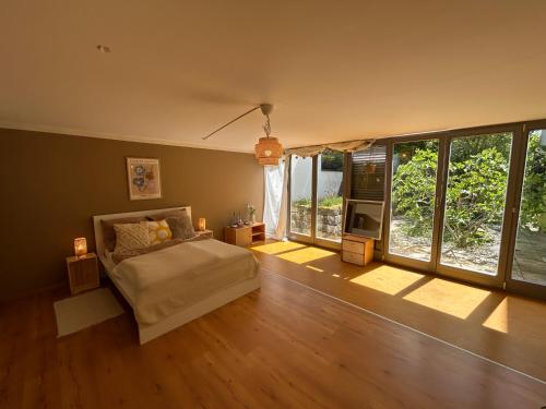 a bedroom with a bed in a room with windows at XXL Schlafzimmer in charmantem Villenanwesen in Heroldsberg