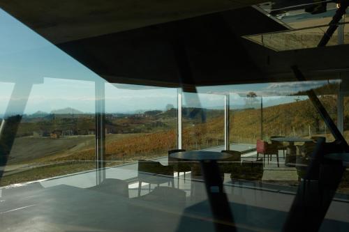 ein Raum mit Tischen und Stühlen und einem großen Fenster in der Unterkunft Cantina dei 5 Sogni in Monforte dʼAlba