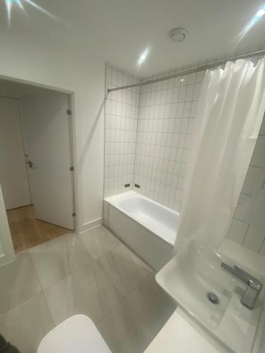 a white bathroom with a toilet and a bath tub at One bedroom apartment with large balcony in Swanley Junction