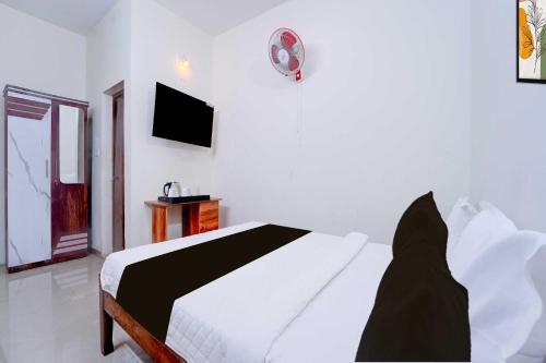 a white bedroom with a bed and a tv at Hotel O Kallar Vattiyar Waterfalls Munnar in Munnar