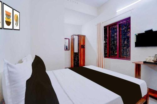 a bedroom with a white bed and a window at Hotel O Kallar Vattiyar Waterfalls Munnar in Munnar