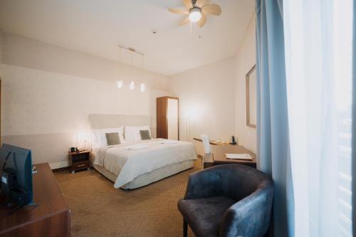a bedroom with a bed and a chair and a television at Hotel Rokoko in Košice