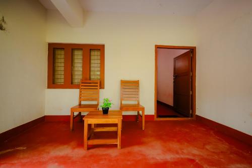 two chairs and a table in a room with a door at Anvitha Mansions in Attigundi