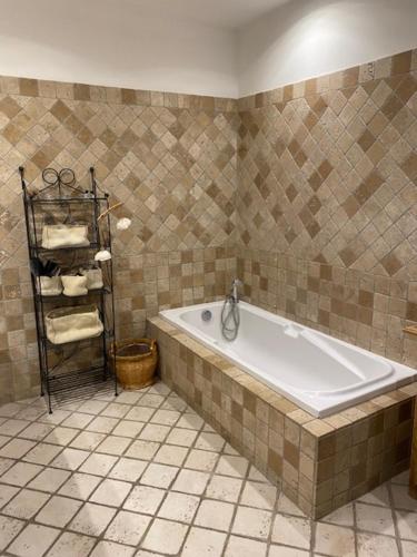 La salle de bains est pourvue d'une baignoire et d'un mur carrelé. dans l'établissement Villa des Rosiers, à La Celle-sous-Gouzon