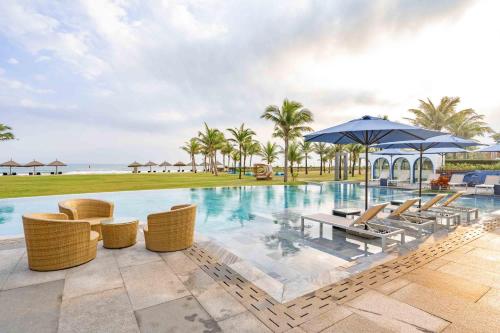 a pool at a resort with chairs and umbrellas at Aqua Vista Hoi An Beachfront Villas in Dien Ban