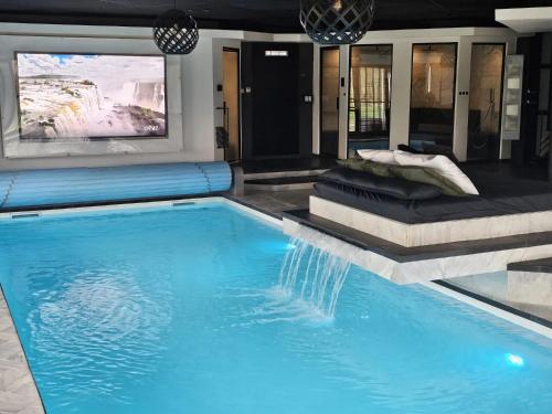 a swimming pool with blue water in a house at Bed & Wellness Malina deluxe in Lelystad