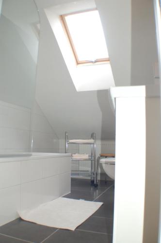 ein weißes Badezimmer mit Oberlicht und Waschbecken in der Unterkunft Wacholder am Waldsee 2 in Rieden