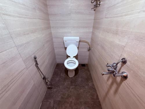 Un baño con un inodoro blanco en una cabina. en Hotel SK Galaxy Thane West, en Thane