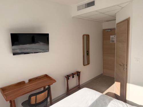a bedroom with a bed and a tv on the wall at Hotel du Village in Village-Neuf