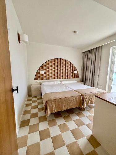 a bedroom with a large bed and a checkered floor at Neptuno Suites - Adults Only in Costa Teguise