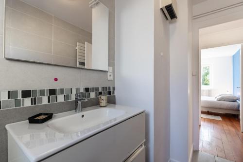 La salle de bains est pourvue d'un lavabo blanc. dans l'établissement Appartement 3 chambres - Gare - Centre-ville, à Bourg-en-Bresse