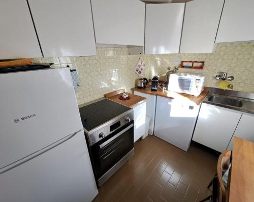 a kitchen with white cabinets and a white refrigerator at Appartamento Croda in Cortina dʼAmpezzo