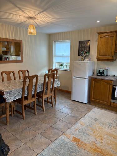 eine Küche mit einem Tisch und einem weißen Kühlschrank in der Unterkunft Moyle Manor in Ballycastle