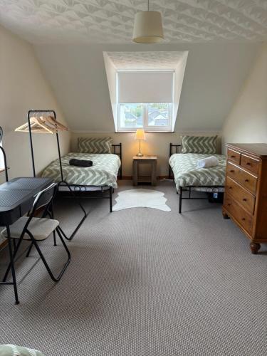 a attic room with two beds and a desk at Moyle Manor in Ballycastle