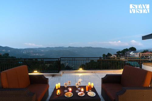 a patio with two chairs and a table with candles at StayVista at Raga Living - Mountain Views, Bonfire in Parwanoo
