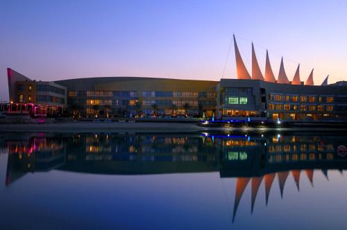 a building with a reflection in a body of water at Dragon Hotel And Resort in Manama