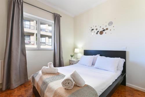 a bedroom with a bed with white sheets and a window at Casa Do Raio City Center Ap By Sé Apartamentos in Braga