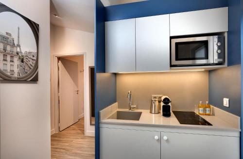 una cocina con fregadero y microondas en Serotel Suites Opera, en París